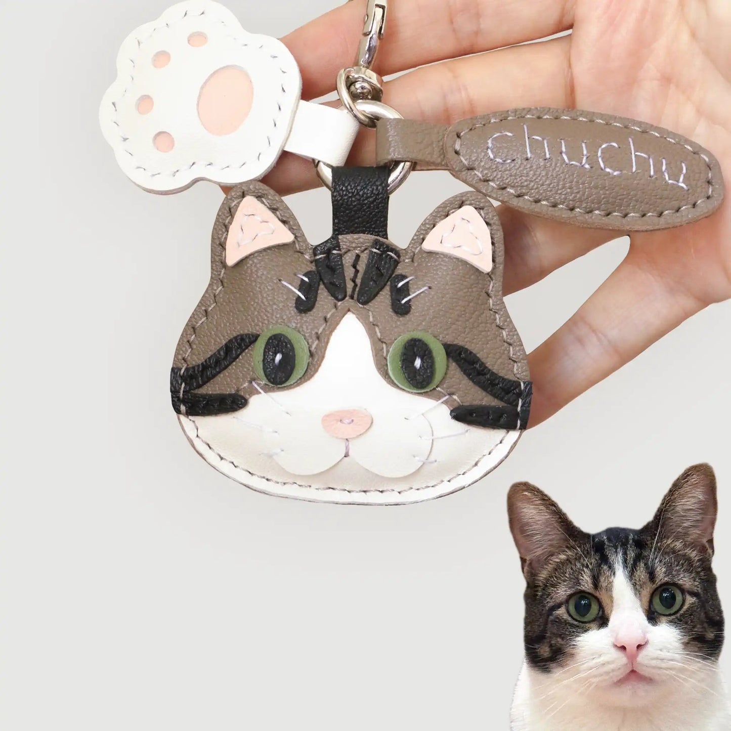 Handcrafted leather charm of Chuchu the tabby cat, custom-made with green eyes and black stripes for a playful likeness.