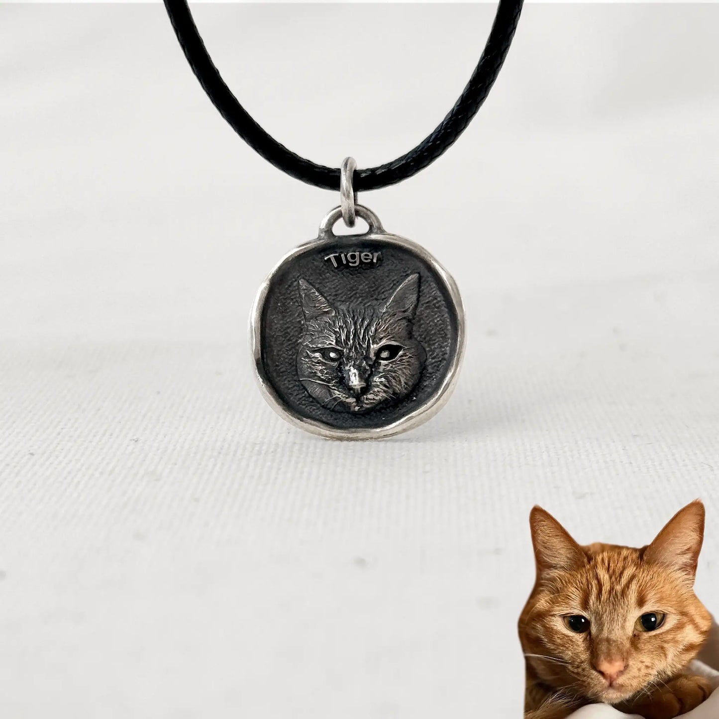 Custom silver cat pendant with engraved portrait of Tiger, ginger tabby cat, on a black cord necklace.