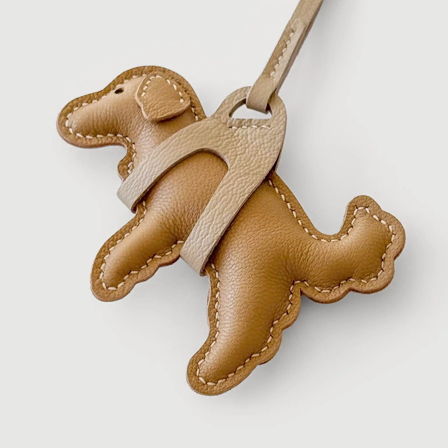 Brown leather dog-shaped keychain on a light gray background