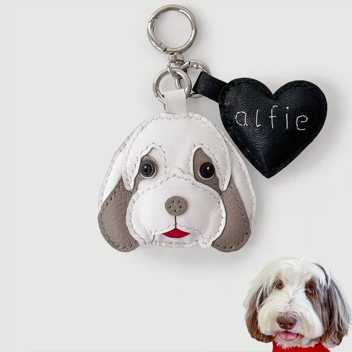 Dog-shaped keychain with a heart-shaped tag and a real dog on a white background