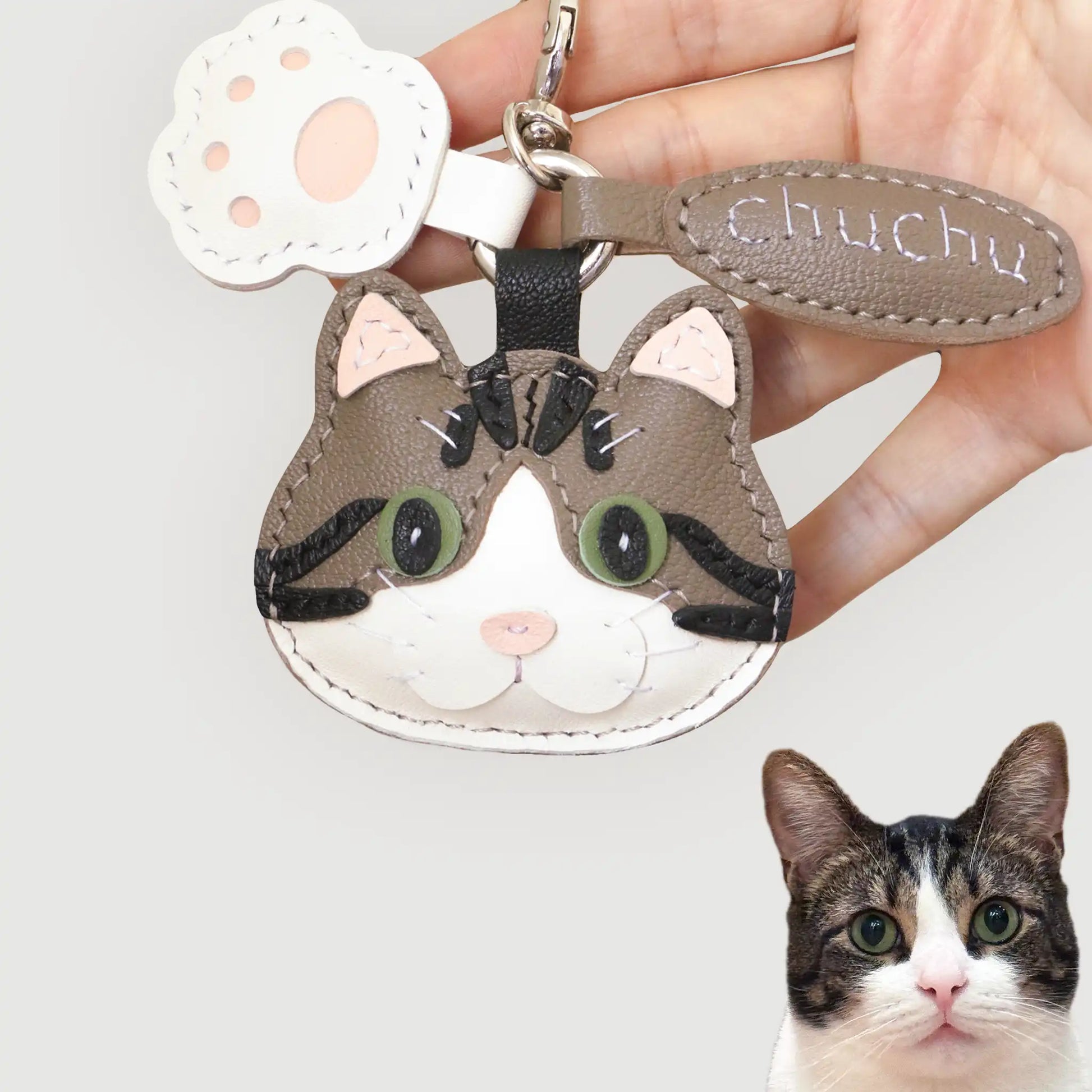 Handcrafted leather charm of Chuchu the tabby cat, custom-made with green eyes and black stripes for a playful likeness.