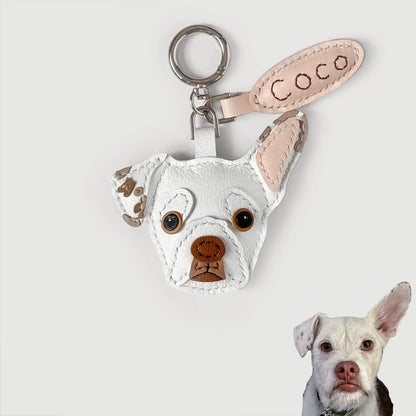 Custom pet leather keychain featuring a white French Bulldog head with brown embroidered details, a light pink ear tab with 'Coco' stitched in brown, and a silver key ring, shown against a light gray background with a small photo of the dog in the bottom right corner.