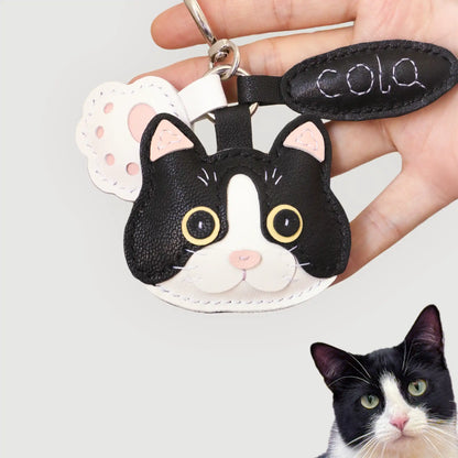 Custom-made leather charm of Cola the tuxedo cat, handcrafted with bold black-and-white leather and bright yellow eyes.