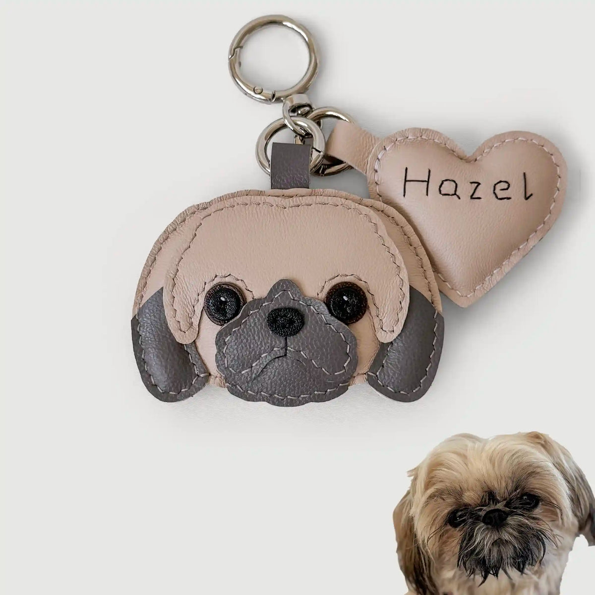 Keychain shaped like a dog's face with a heart tag labeled 'Hazel' on a white background.
