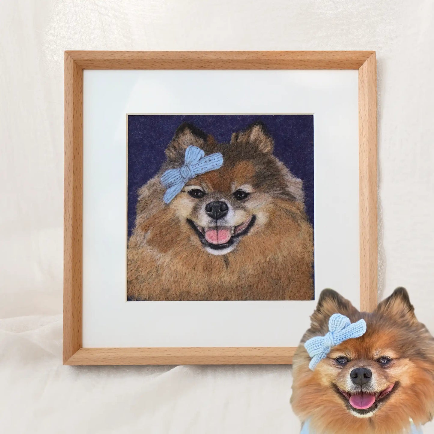 Custom-made wool felt pet portrait of Bella the Pomeranian, smiling with a blue bow, framed as soft-textured dog artwork.