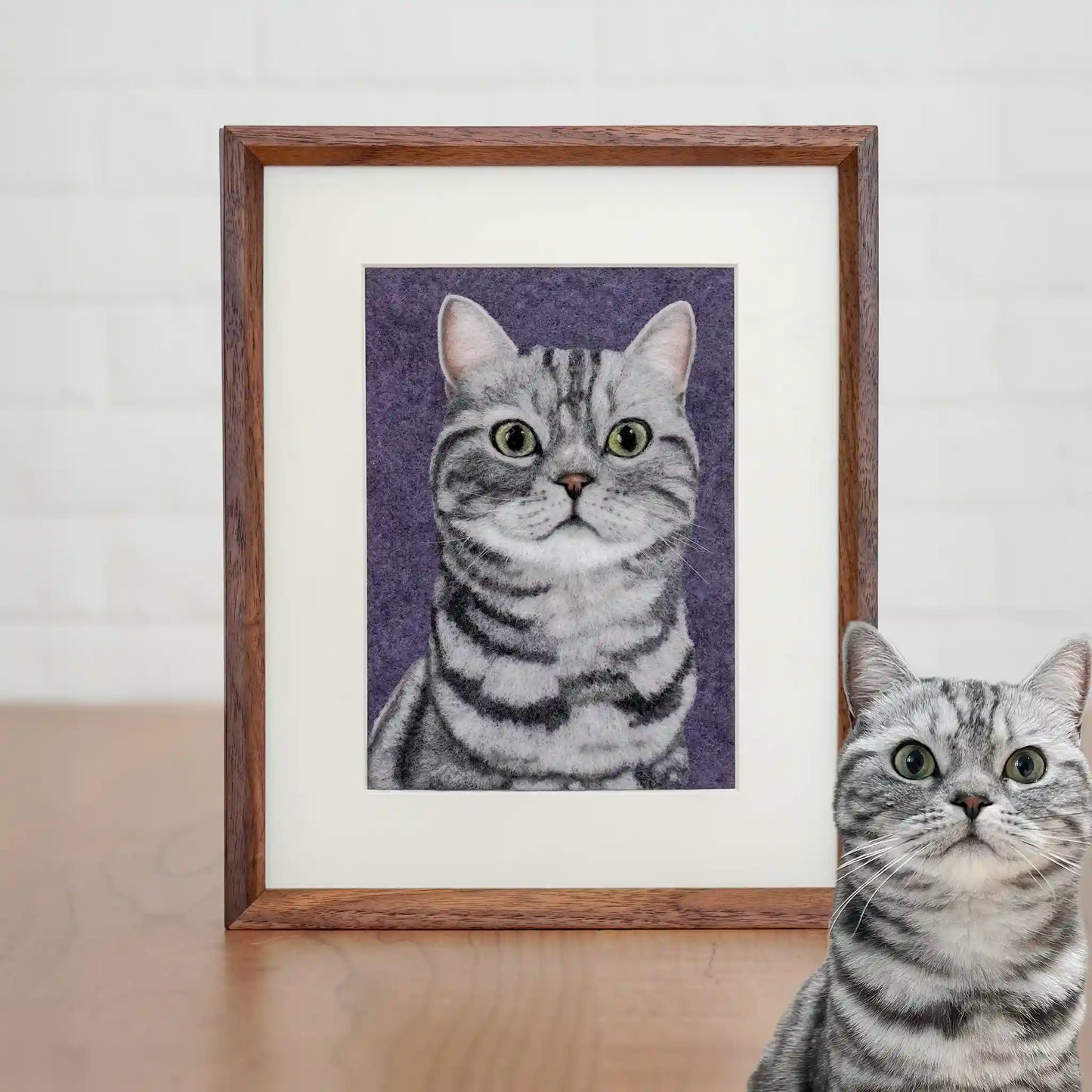 Wool felt portrait of Lianlian the silver American Shorthair, with green eyes and stripes, framed on a purple background.