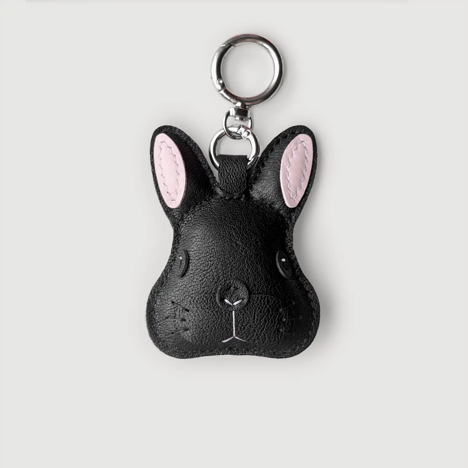 Black rabbit-shaped keychain with pink ears on a light gray background