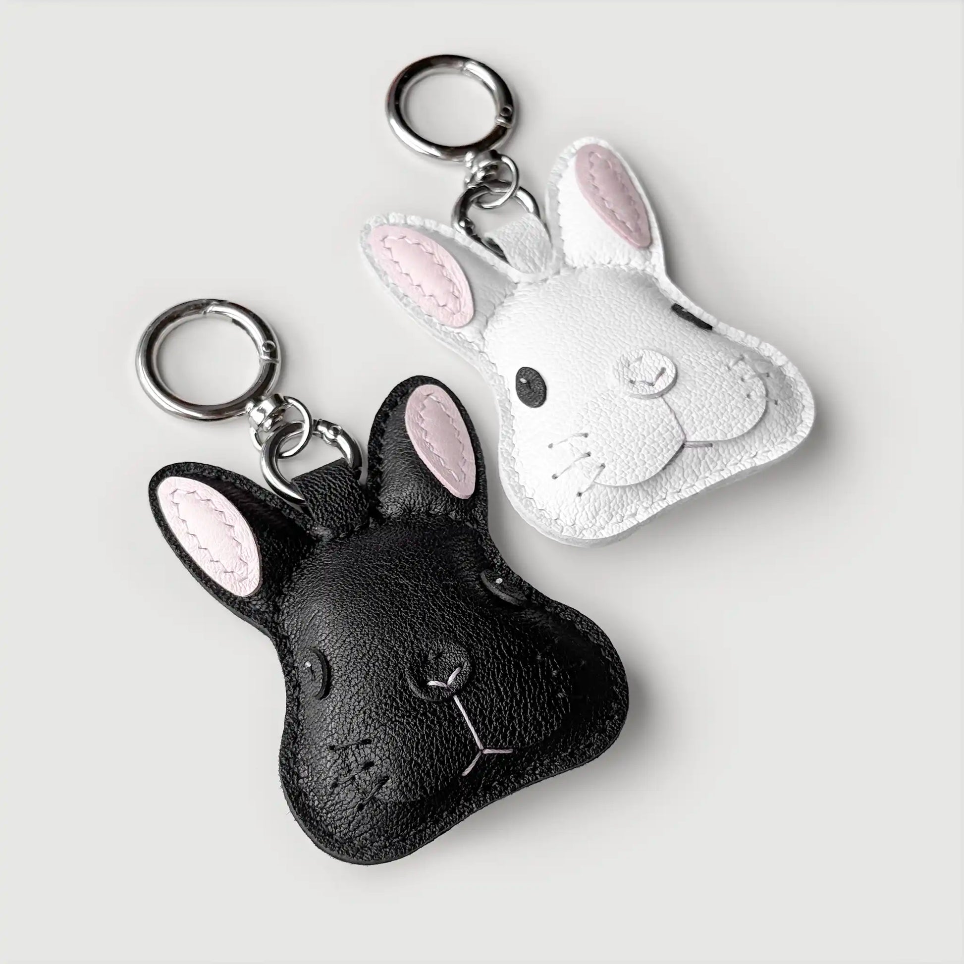 Black and silver rabbit-shaped keychains on a light gray background