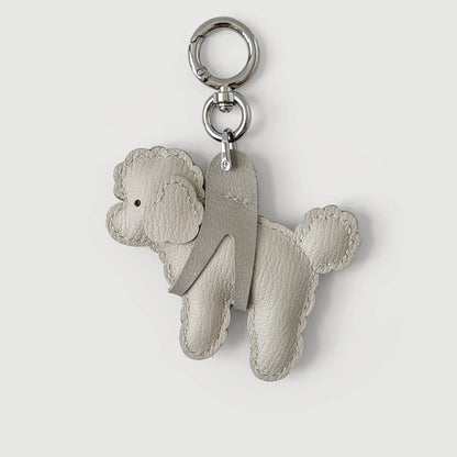 A light gray leather poodle-shaped keychain with a silver-tone split ring and key ring, shown on a light gray background.